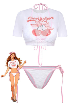 Completo da bagno composto da tre pezzi, una maglietta corta bianca con la scritta "Cherry Love" e un bikini coordinato con trama floreale e finiture rosa.
