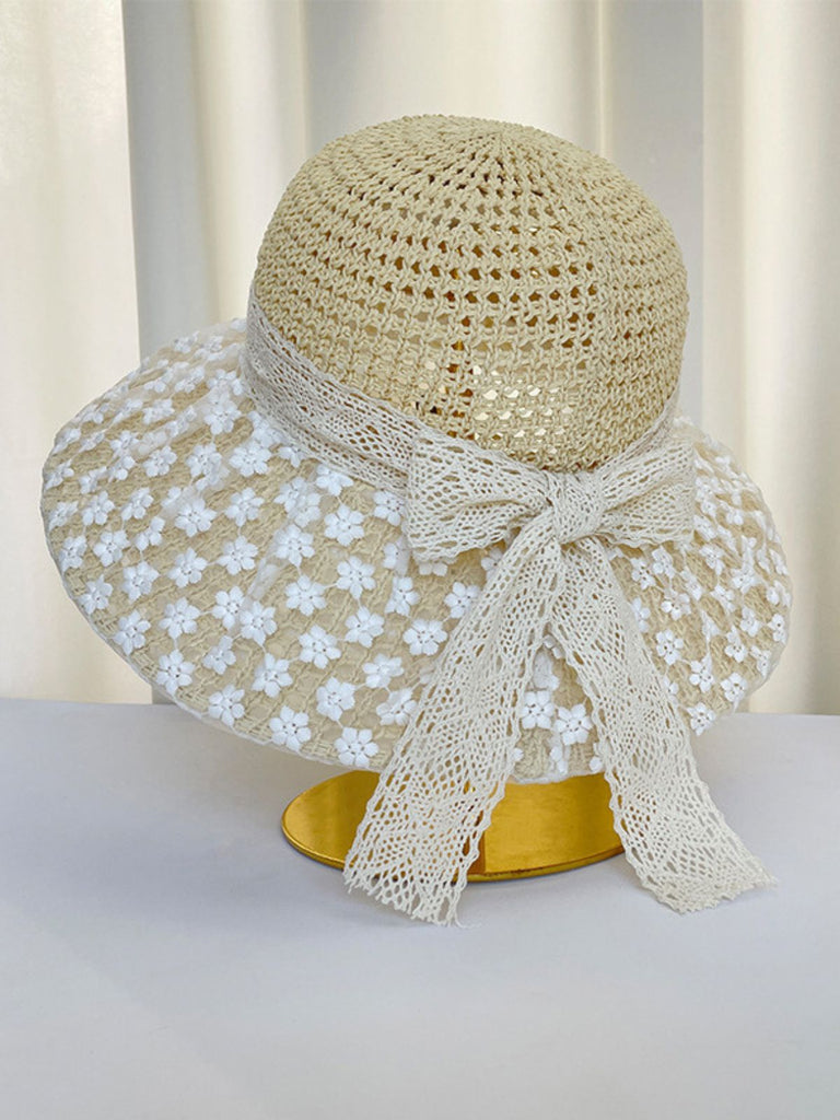 Cappello da sole beige con rifiniture in pizzo floreale bianco su sfondo bianco
