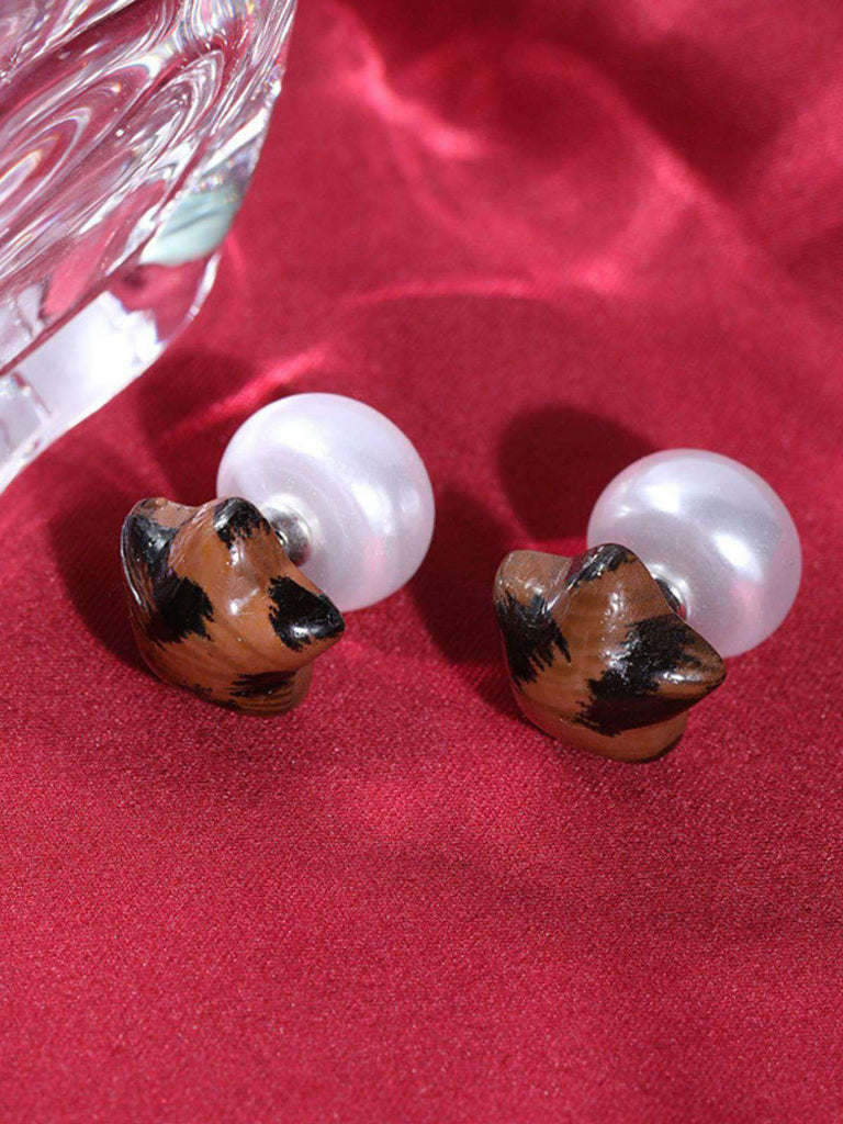 Dog-shaped earrings with white centers on a red fabric background