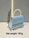 Light blue handbag with pearl handle on a textured gray background