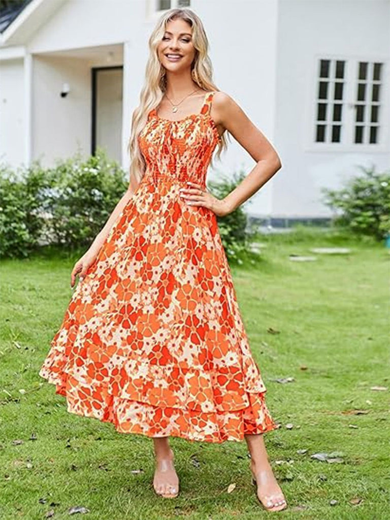 Woman wearing an orange floral dress standing on grass with a house in the background