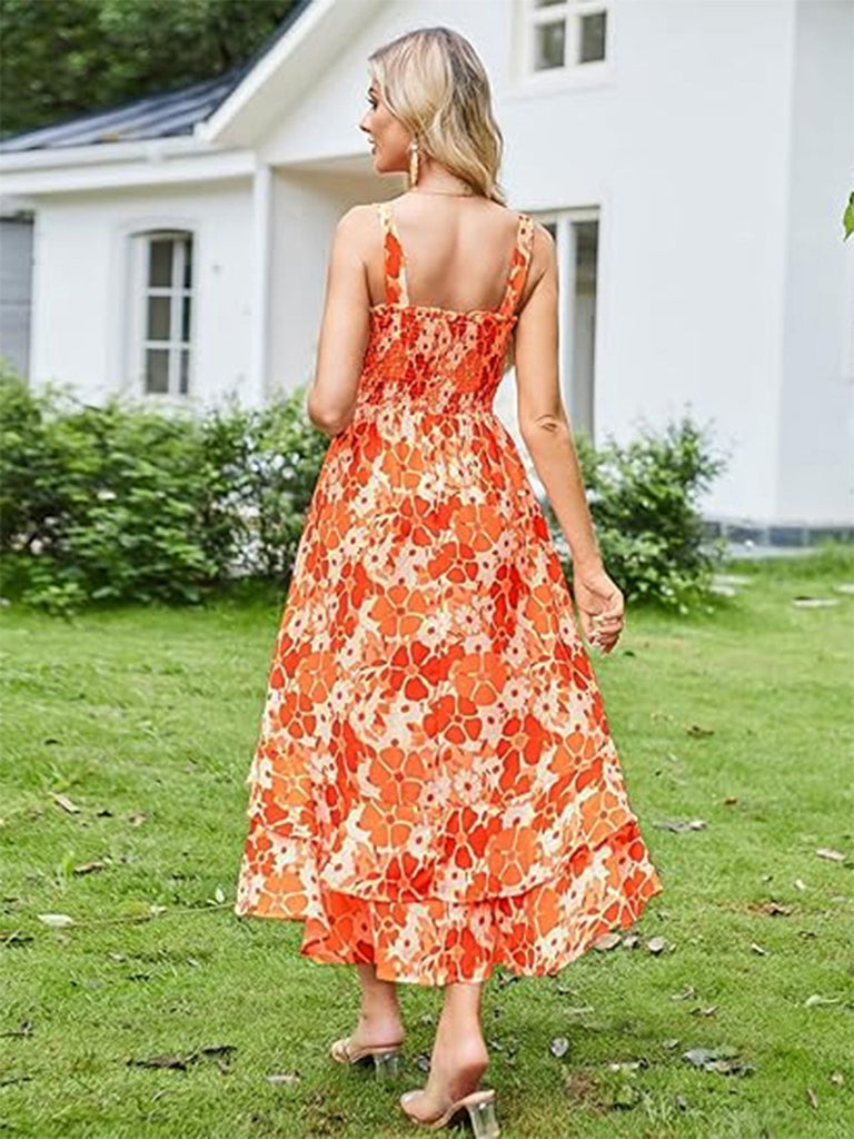 Woman in an orange floral dress standing on grass with a white house in the background