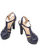 A pair of navy blue retro-style high-heeled sandals with adjustable ankle buckles and a classic T-strap design.